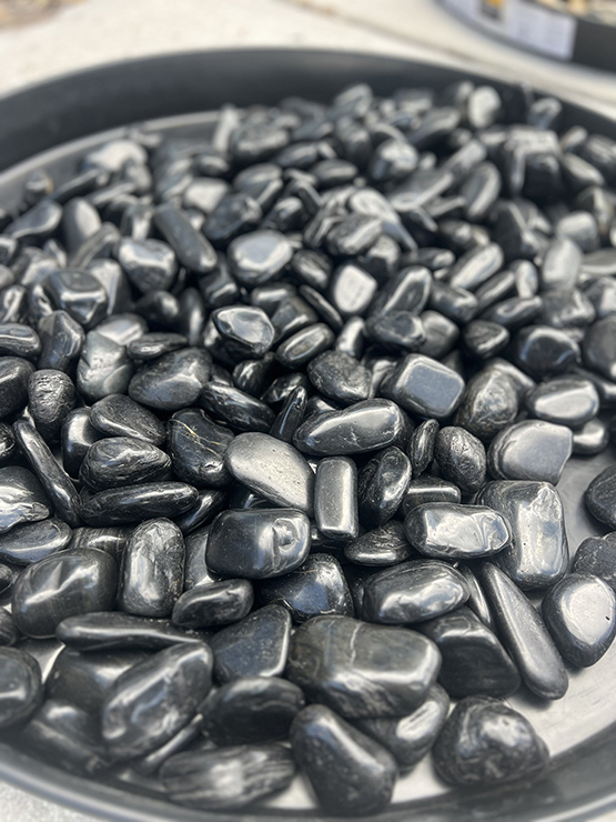 Black polished pebbles installed in landscape bed